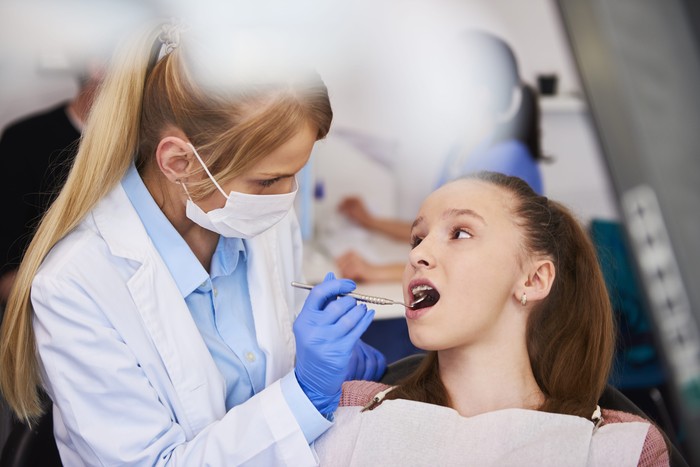 female-orthodontist-examining-child-s-teeth-min