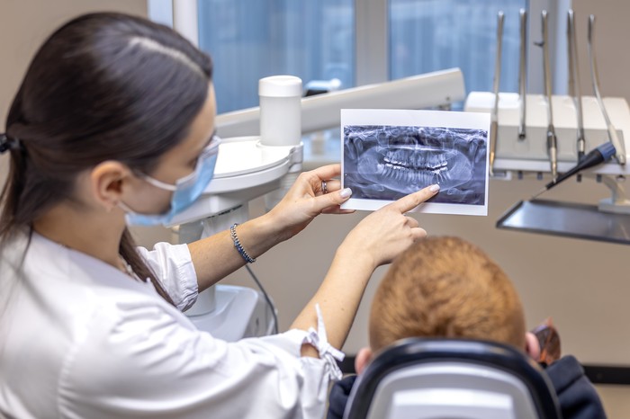 young-female-dentist-showing-patient-dental-xray-dentistry-concept-min